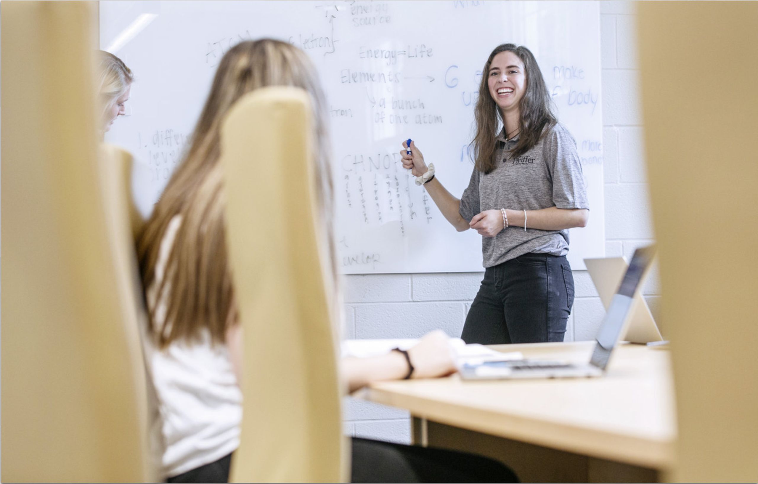 woman smiling and pointing to whiteboard