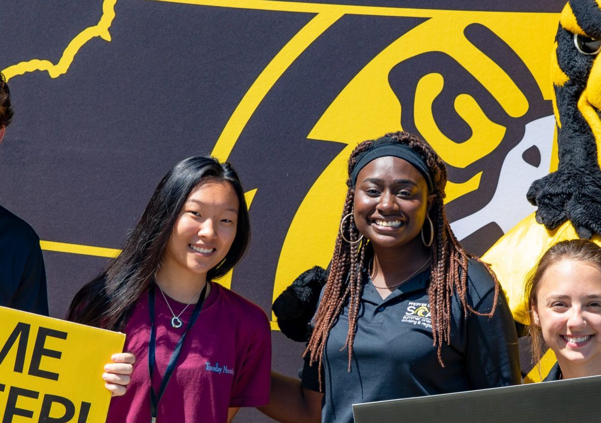 Group of students with Pfeiffer mascot and welcome sign