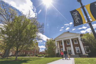 blue sky shining on pfeiffer building with students walking dog