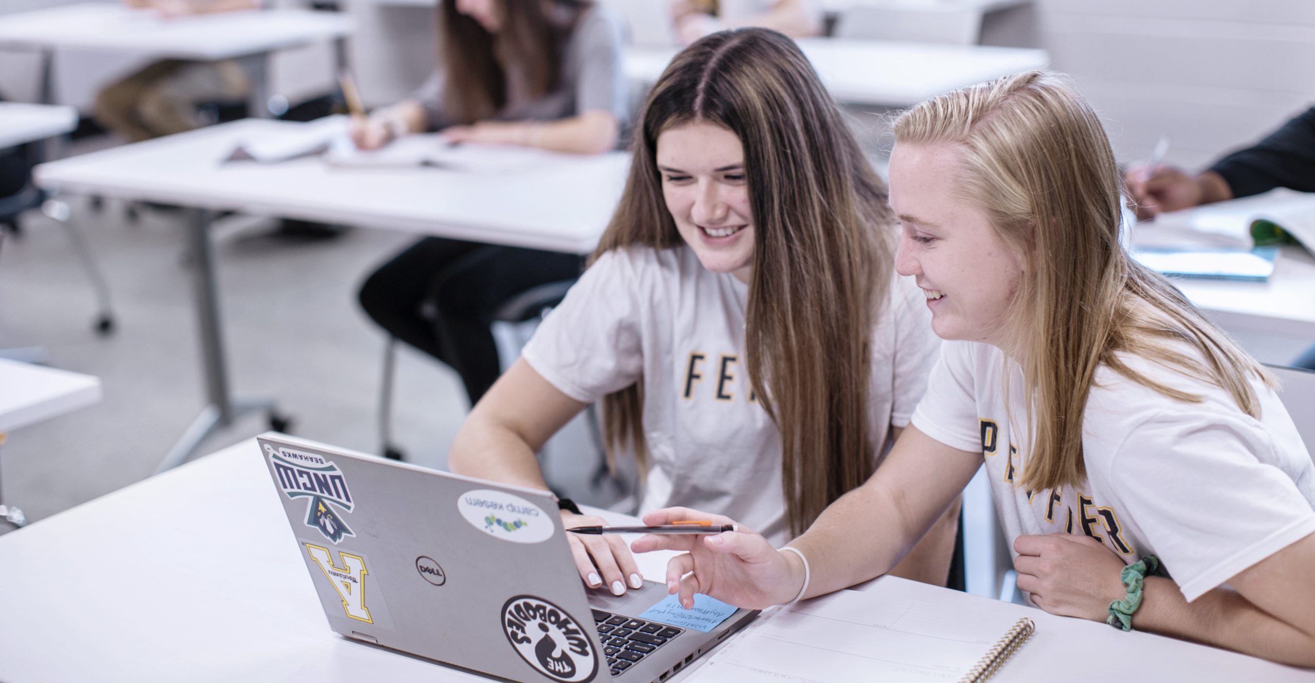 Two students working on a laptop in a classroom