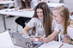 Two students working on a laptop in a classroom