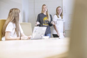 2 girls talking to another girl in a classroom