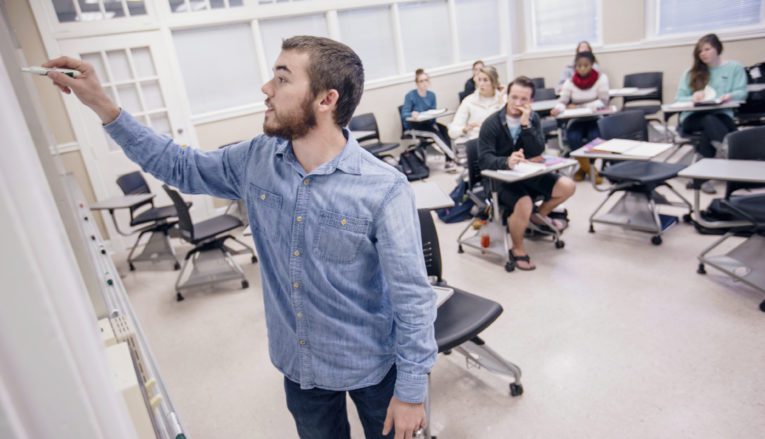 Professor writing on whiteboard in class