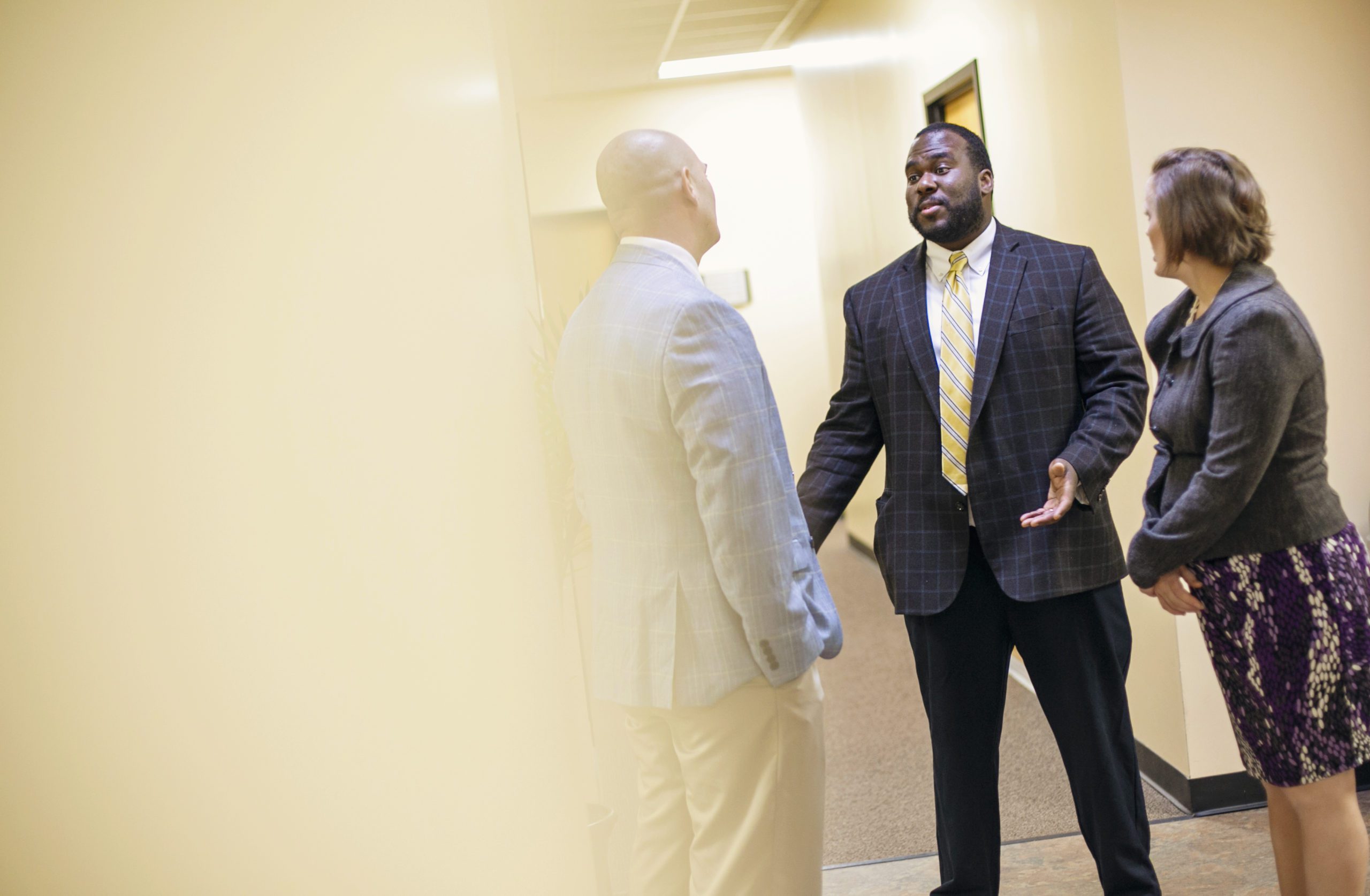 Three professors speaking to each other in hallway