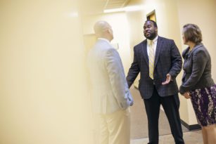 Three professors speaking to each other in hallway