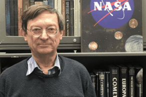 Man in front of bookshelf and NASA sign