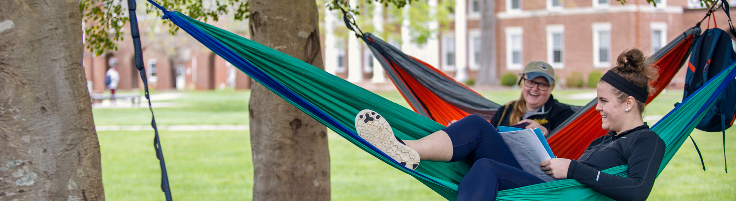 Two students sitting in hammocks outside