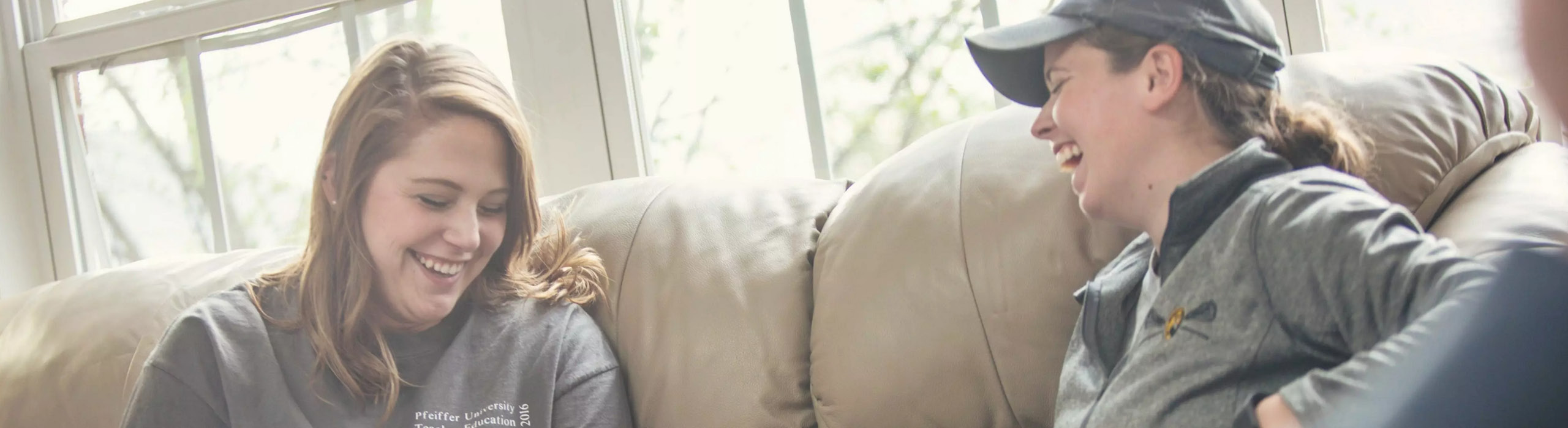 Two students sitting on couch laughing